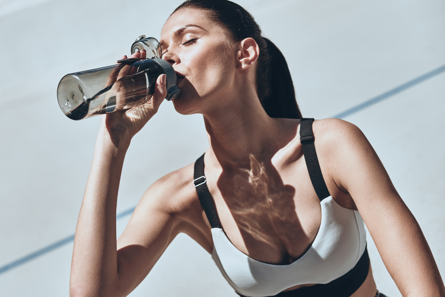 Image représentant une femme sportive en train de boire de l'eau dans sa gourde.