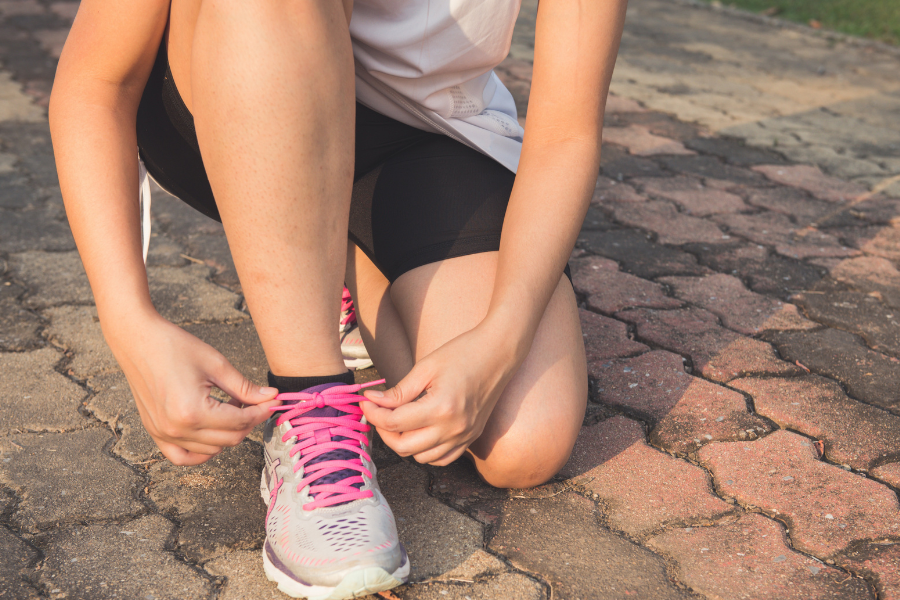 Femme en train de lacer ses chaussures avant de courir.