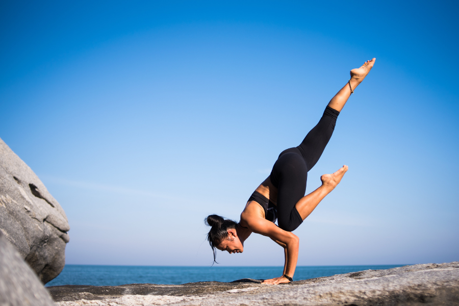 Femme en train de pratiquer le yoga face à la mer.