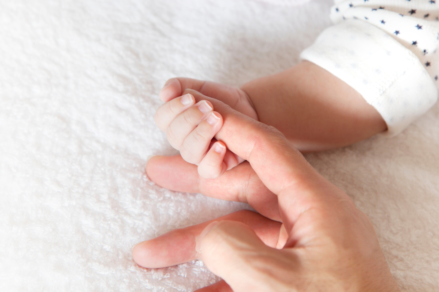 bebe serrant le doigt d un adulte. microbiote et allergies saisonnieres