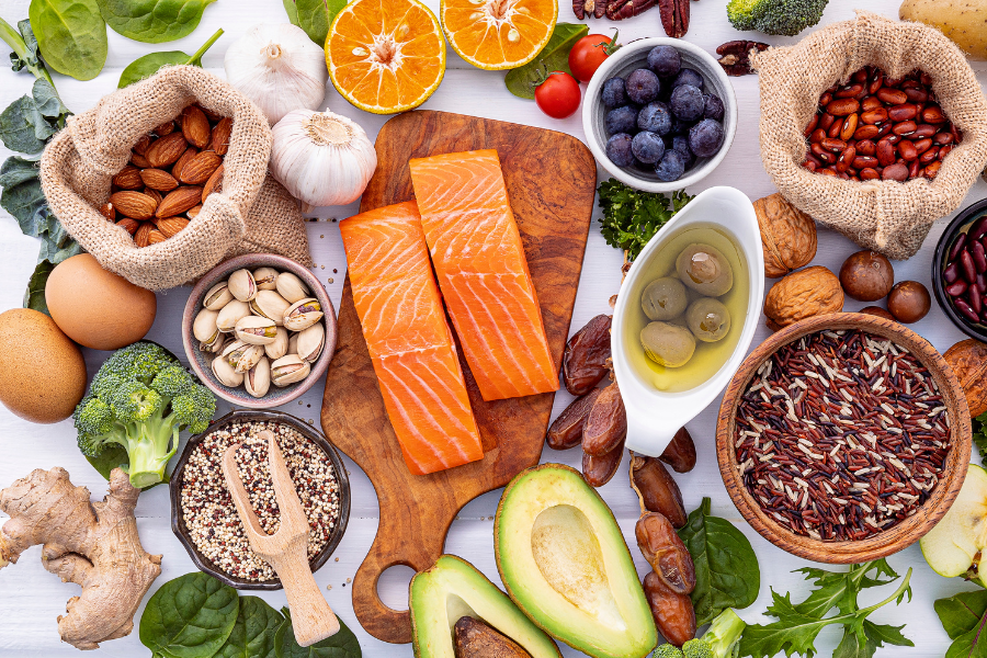 table sur laquelle sont poses des aliments sains tels que du poisson, des oleagineux, des cereales completes, des oeufs, des fruits et legumes