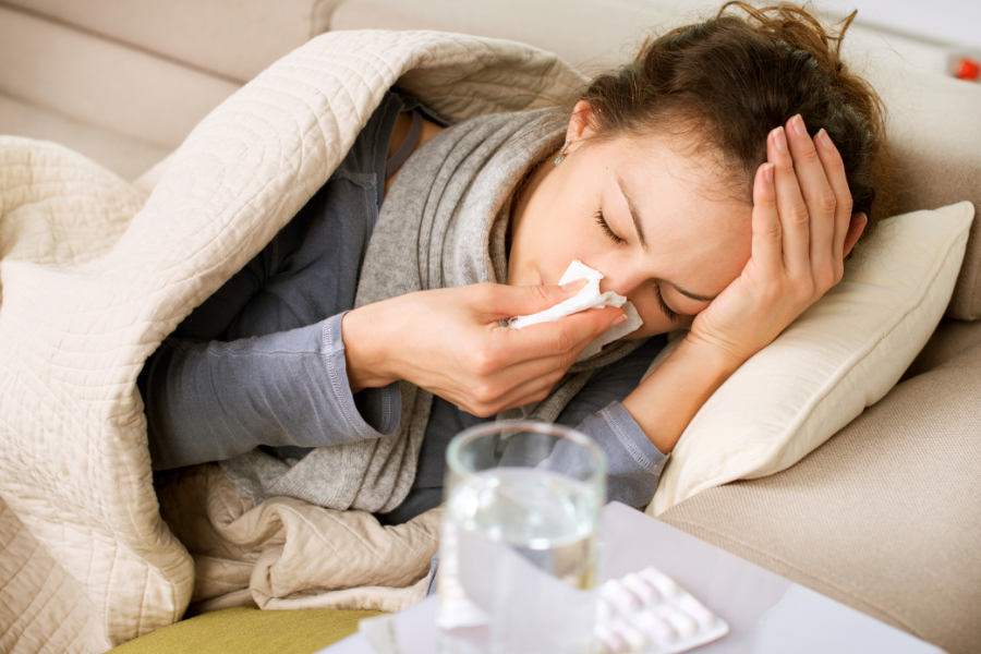 femme malade sous un plaid en train de se moucher. microbiote et defenses immunitaires